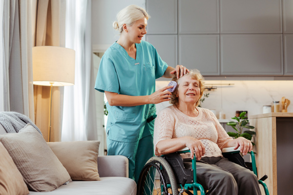 caregiver assisting elderly woman in wheelchair at home with personal grooming Senior care professional services