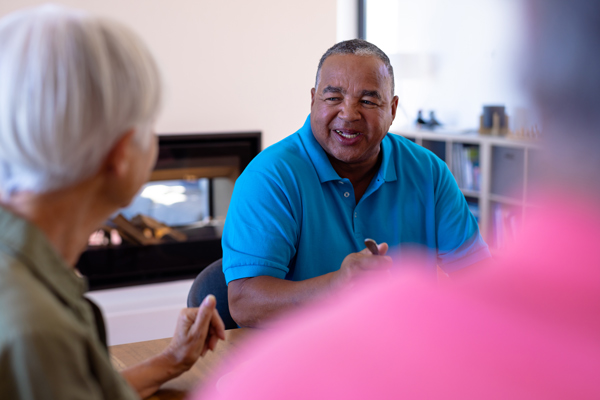 smiling man talking to a group in a casual setting discussing senior community engagement and wellbeing